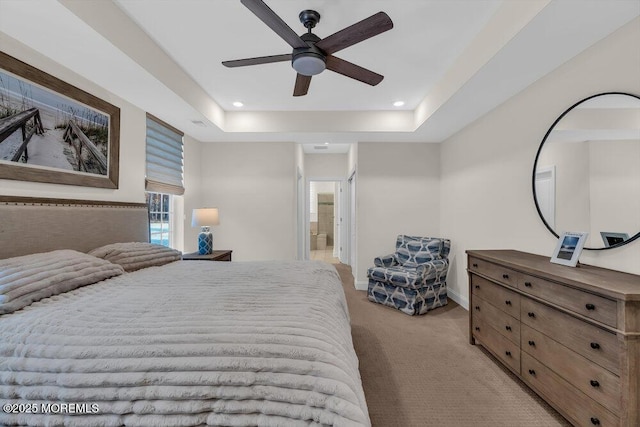 carpeted bedroom with ceiling fan, ensuite bath, and a tray ceiling