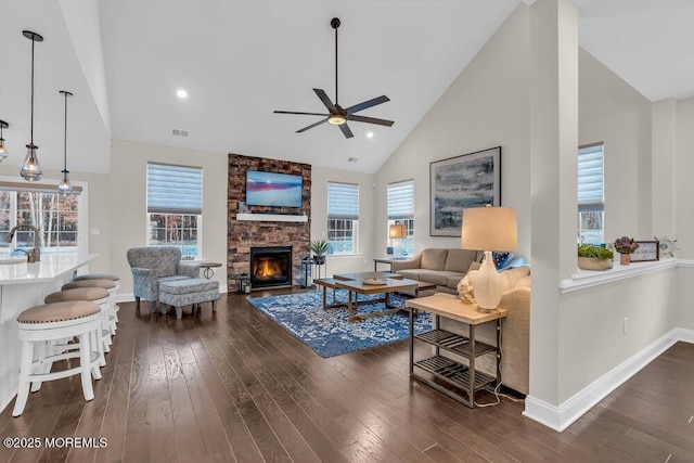 living room with a fireplace, high vaulted ceiling, sink, ceiling fan, and dark wood-type flooring