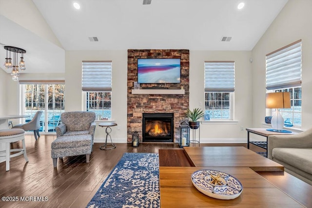 living room with a stone fireplace, vaulted ceiling, and plenty of natural light