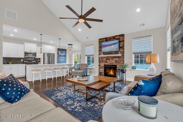 living room with ceiling fan, dark hardwood / wood-style floors, a fireplace, and high vaulted ceiling