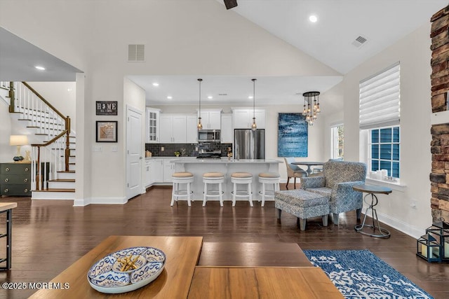 living room with dark hardwood / wood-style flooring, a chandelier, and high vaulted ceiling