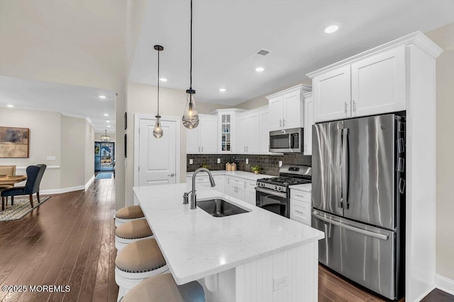 kitchen featuring stainless steel appliances, an island with sink, sink, and decorative light fixtures