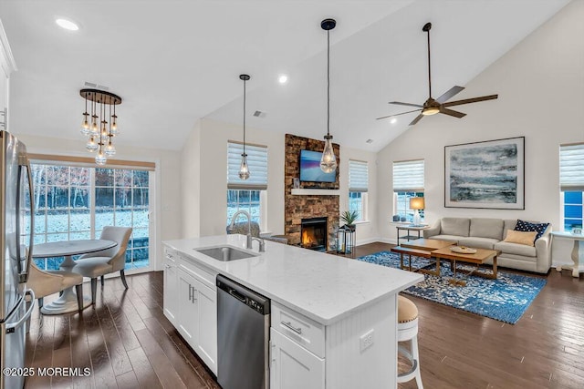 kitchen with sink, appliances with stainless steel finishes, dark hardwood / wood-style flooring, a kitchen island with sink, and white cabinets