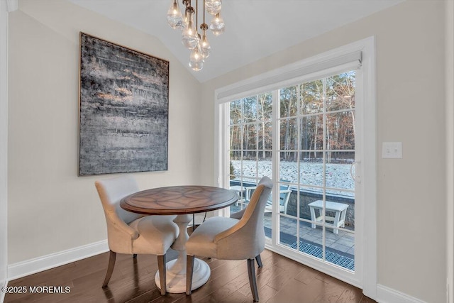 dining space with dark hardwood / wood-style floors, a chandelier, and vaulted ceiling