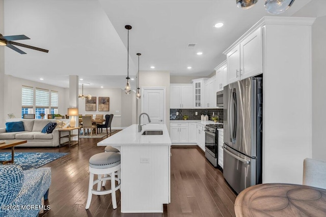 kitchen featuring sink, white cabinetry, stainless steel appliances, a kitchen island with sink, and decorative backsplash