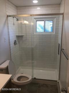 bathroom featuring baseboard heating, vanity, toilet, and a shower with shower door