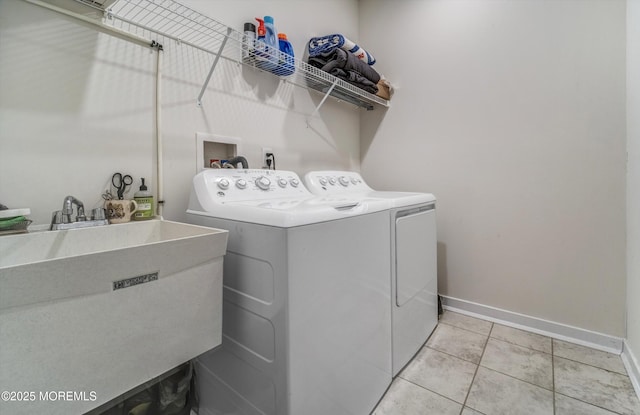 clothes washing area with sink, washer and dryer, and light tile patterned flooring