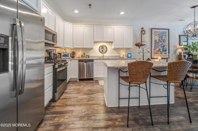 kitchen featuring white cabinetry, appliances with stainless steel finishes, and hanging light fixtures