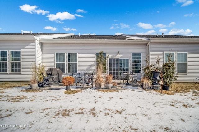 snow covered rear of property with a patio