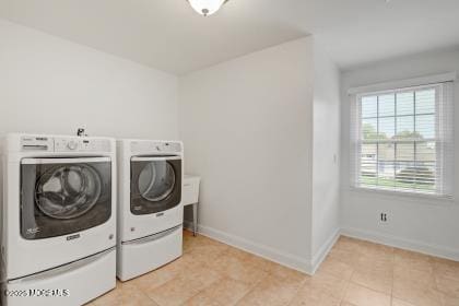 clothes washing area with light tile patterned flooring and washer and clothes dryer