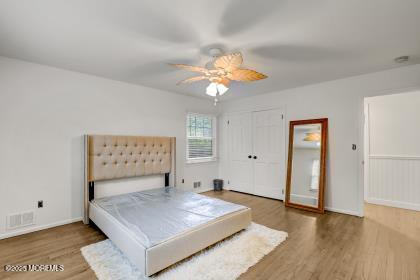 bedroom featuring wood-type flooring, ceiling fan, and a closet