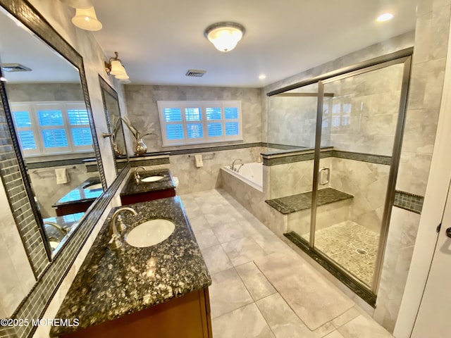 bathroom with vanity, shower with separate bathtub, and tile walls