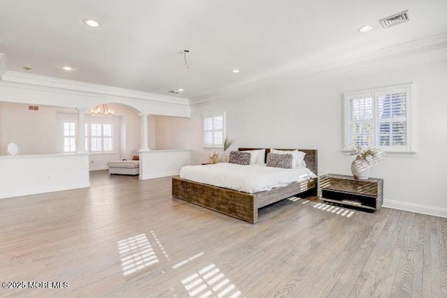 bedroom featuring crown molding, light hardwood / wood-style floors, multiple windows, and ornate columns