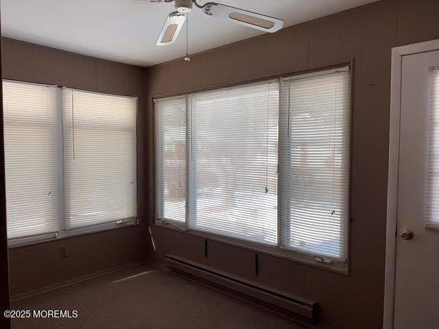 unfurnished sunroom featuring ceiling fan and baseboard heating