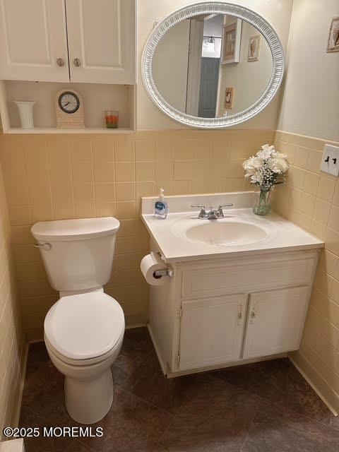 bathroom with vanity, toilet, and tile walls