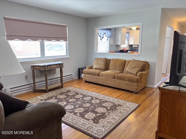 living room featuring a baseboard heating unit and light hardwood / wood-style flooring