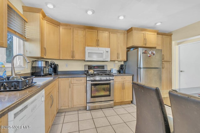 kitchen featuring light tile patterned flooring, stainless steel appliances, light brown cabinetry, and sink