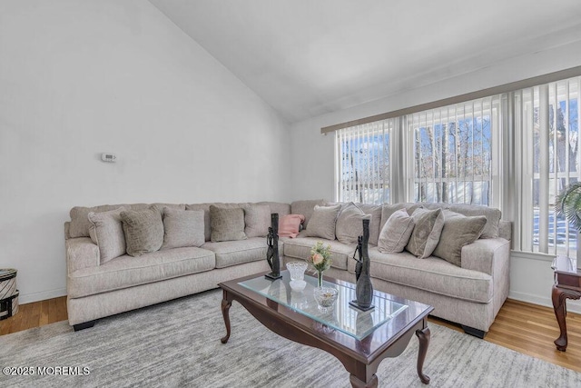 living room featuring lofted ceiling, light hardwood / wood-style flooring, and plenty of natural light