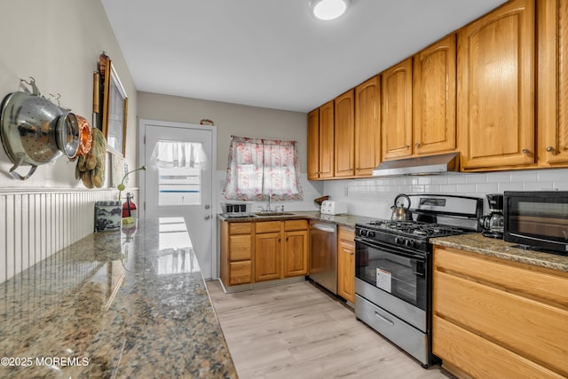 kitchen featuring dishwasher, sink, backsplash, dark stone counters, and gas stove