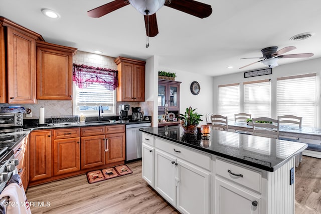 kitchen featuring white cabinetry, tasteful backsplash, stainless steel dishwasher, and light wood-type flooring