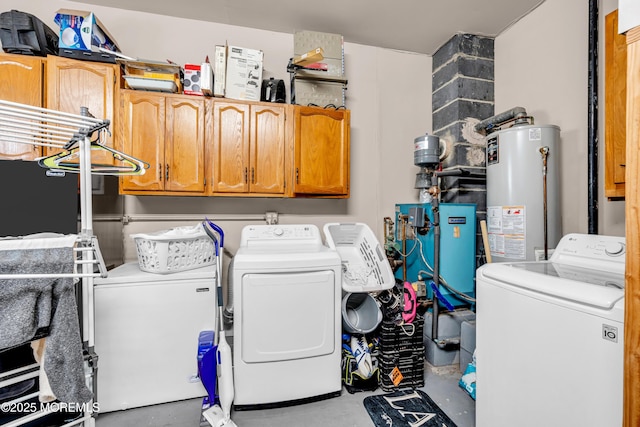 laundry room with water heater, washing machine and clothes dryer, and cabinets