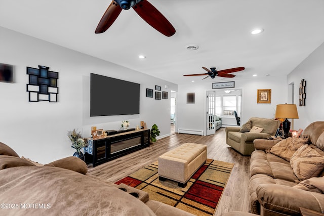 living room with ceiling fan, baseboard heating, and light hardwood / wood-style flooring