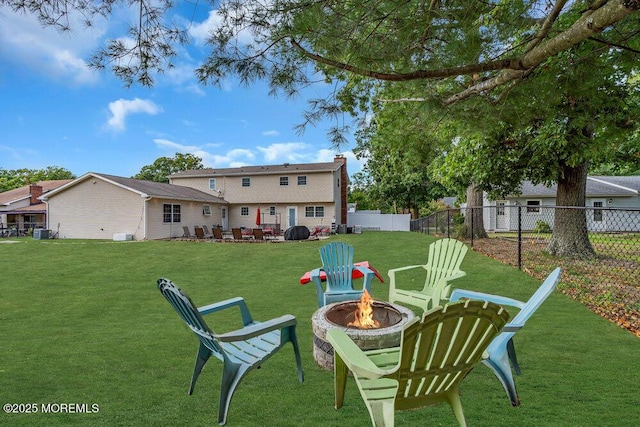 back of property featuring a lawn and an outdoor fire pit