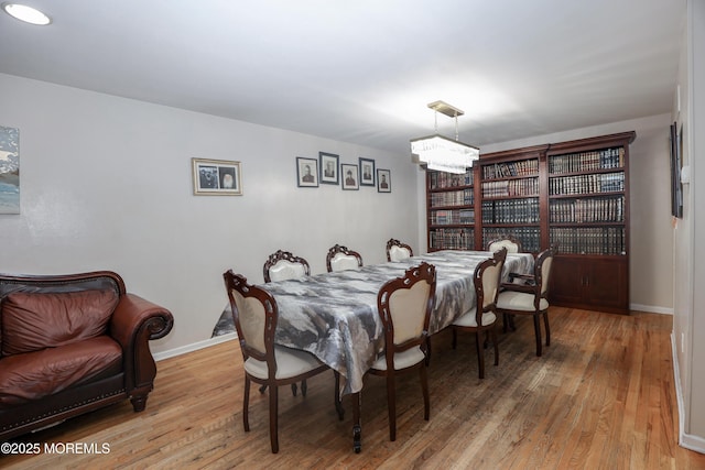 dining space with hardwood / wood-style floors and a notable chandelier