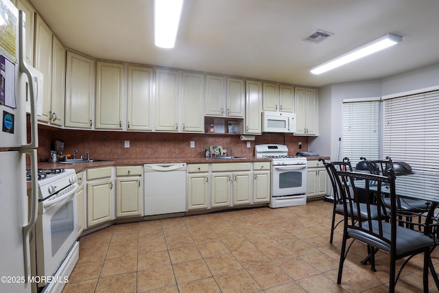 kitchen featuring white appliances, cream cabinets, sink, and light tile patterned floors