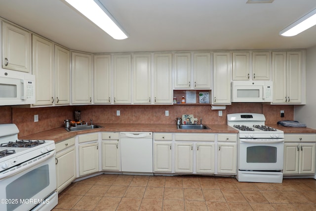 kitchen featuring tasteful backsplash, sink, light tile patterned floors, and white appliances