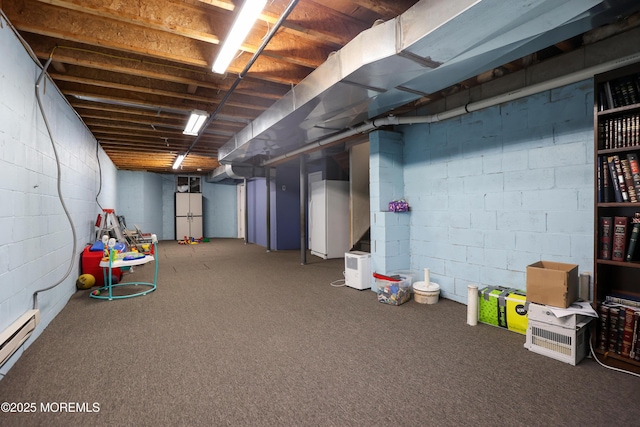 basement featuring a baseboard heating unit, white fridge, and carpet