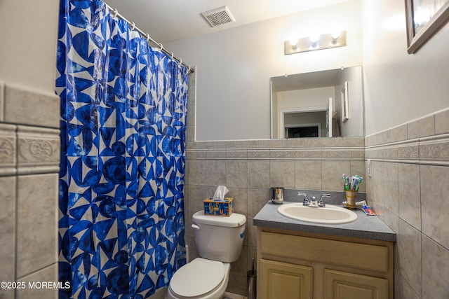 bathroom featuring vanity, toilet, and tile walls