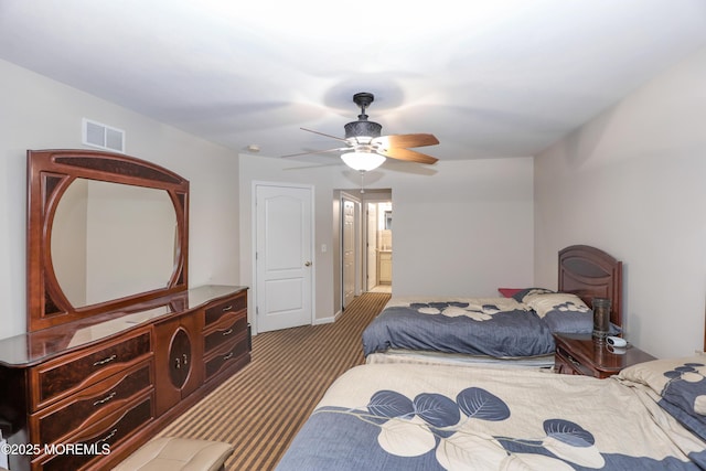 carpeted bedroom with ensuite bathroom and ceiling fan