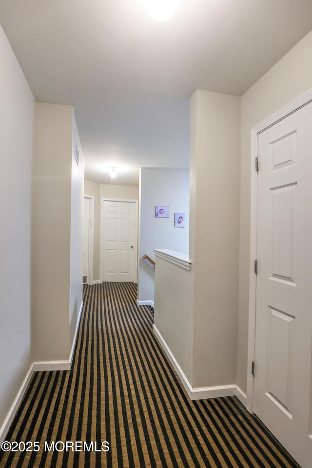 corridor featuring dark colored carpet