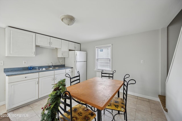 kitchen featuring sink, light tile patterned flooring, white cabinets, and white fridge