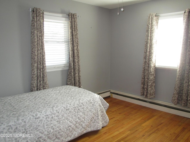 bedroom featuring a baseboard heating unit and wood-type flooring