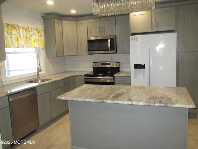 kitchen featuring appliances with stainless steel finishes, a center island, sink, and backsplash