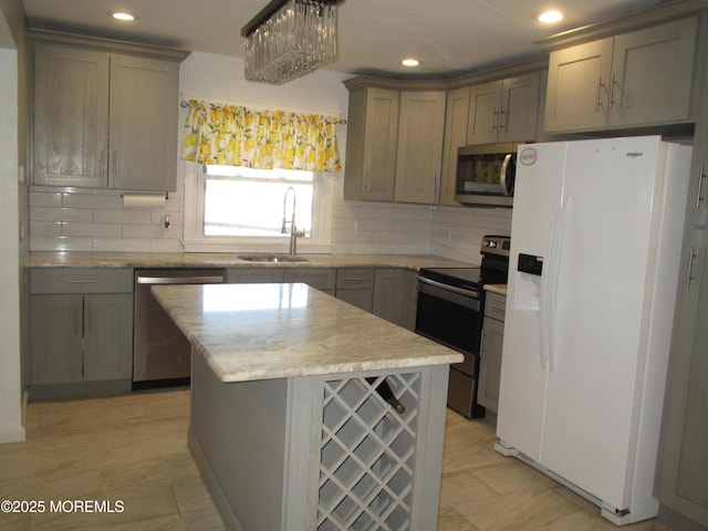 kitchen featuring appliances with stainless steel finishes, decorative light fixtures, sink, decorative backsplash, and a center island