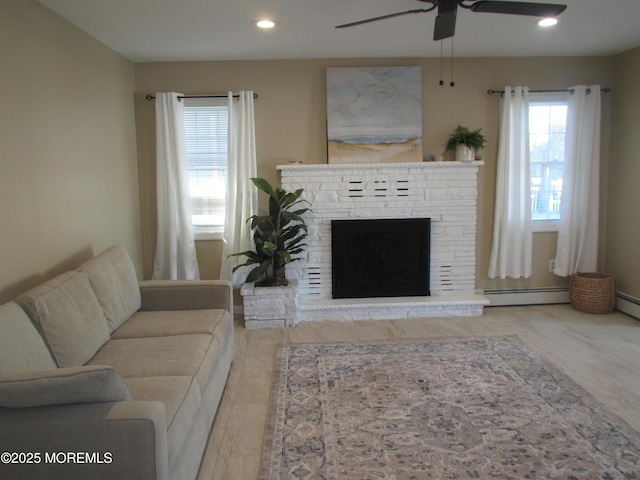 living room with a baseboard radiator, ceiling fan, and a fireplace