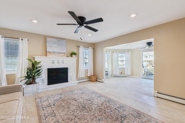 unfurnished living room with ceiling fan, a baseboard radiator, and a fireplace