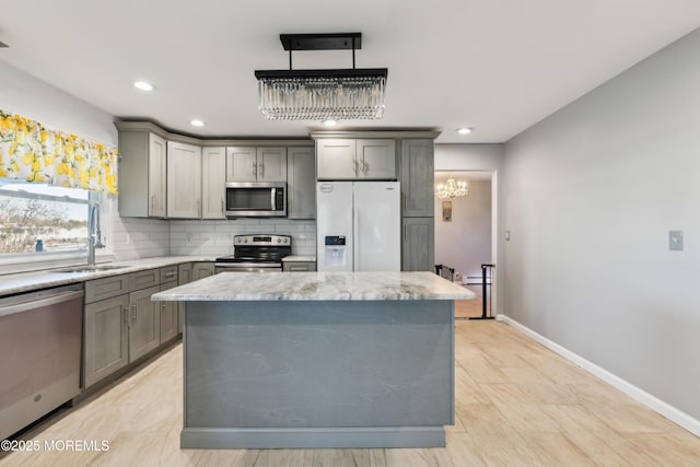 kitchen with sink, decorative light fixtures, a center island, appliances with stainless steel finishes, and gray cabinets