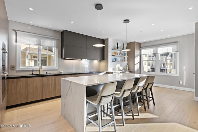 kitchen with sink, a breakfast bar, dark stone countertops, a kitchen island, and decorative light fixtures