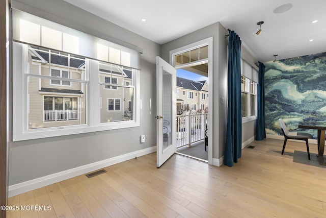 doorway to outside featuring a wealth of natural light and light hardwood / wood-style floors