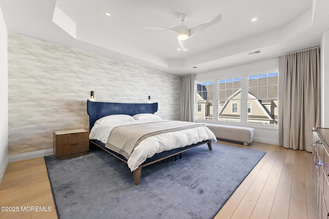 bedroom featuring hardwood / wood-style flooring, ceiling fan, and a tray ceiling