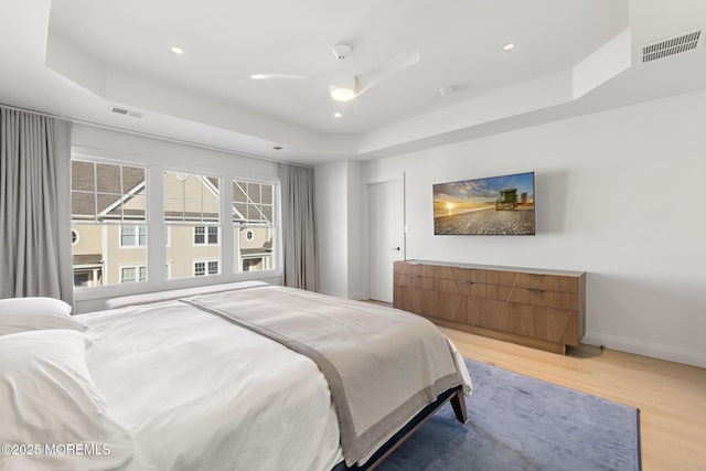 bedroom with a raised ceiling, hardwood / wood-style flooring, and ceiling fan