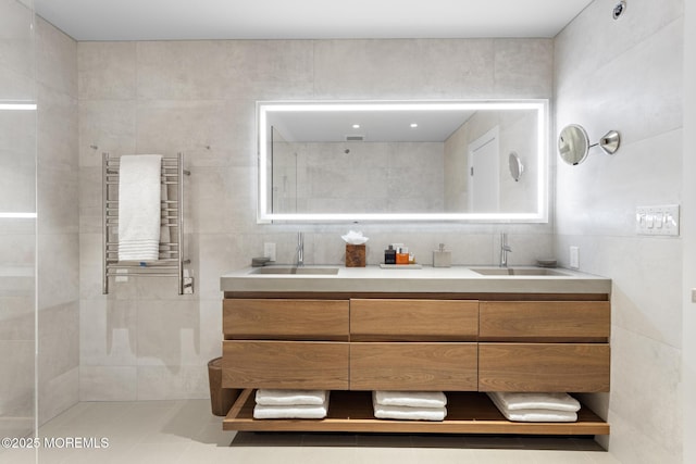 bathroom featuring tile patterned floors, vanity, radiator, and tile walls