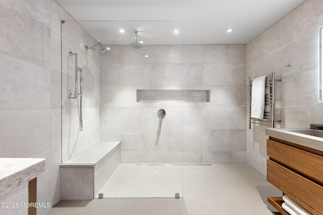 bathroom with vanity, radiator, tile walls, and tiled shower