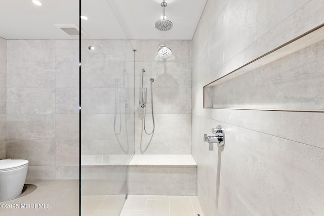 bathroom featuring a tile shower and toilet