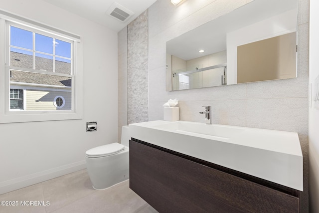 bathroom with tile walls, vanity, decorative backsplash, a shower with shower door, and toilet