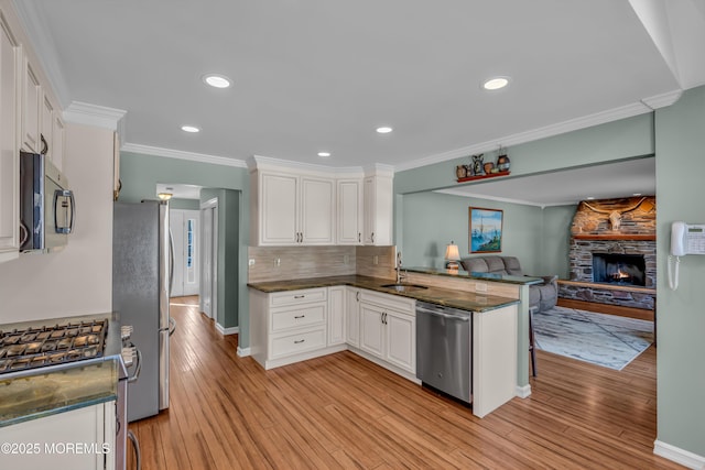 kitchen featuring crown molding, light hardwood / wood-style flooring, white cabinetry, stainless steel appliances, and kitchen peninsula